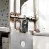 Combination padlock securing a rusted metal gate in an industrial setting